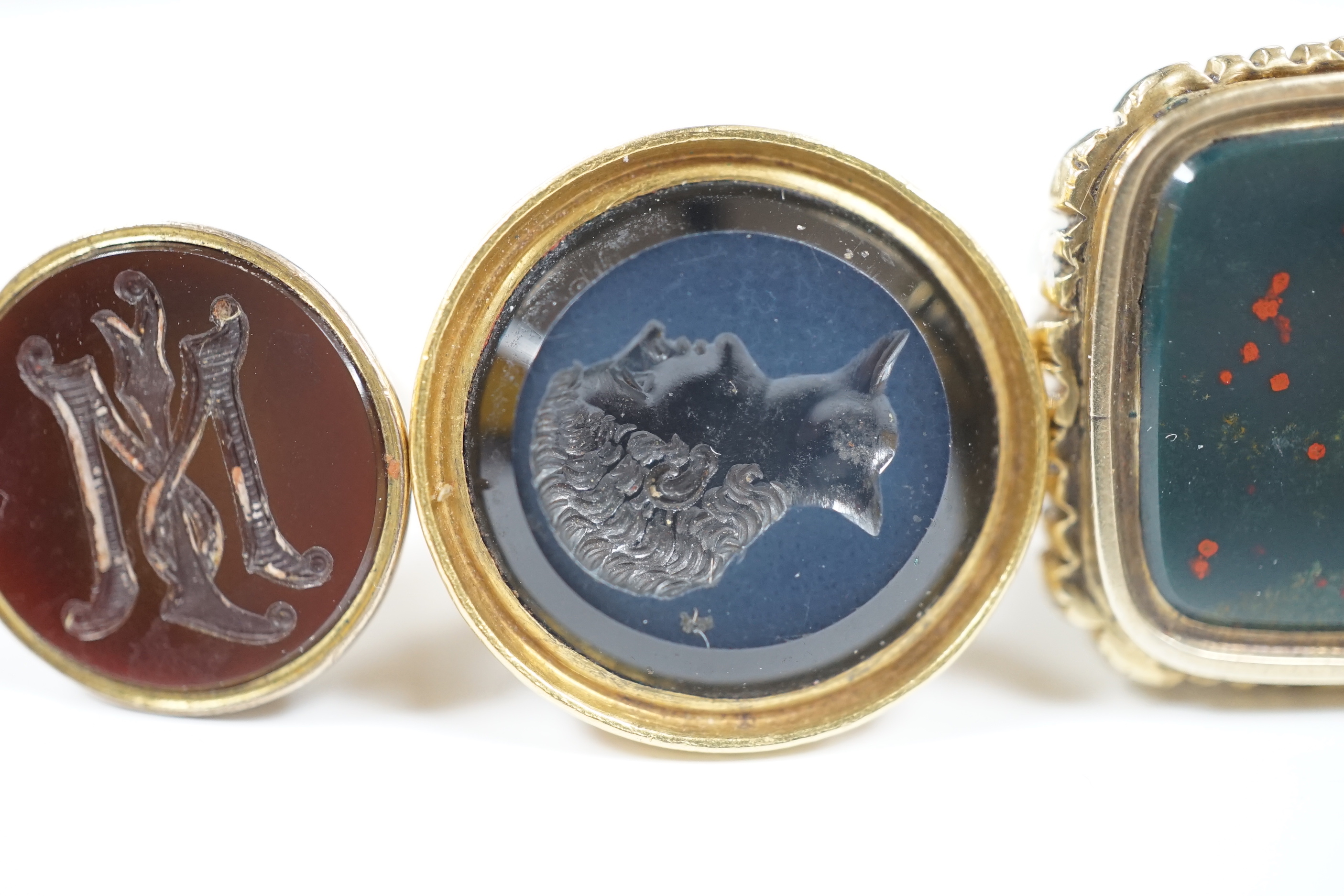 Three assorted Victorian and later yellow metal overlaid and chalcedony set fob deals, including intaglio bust of a gentleman, largest 35mm.